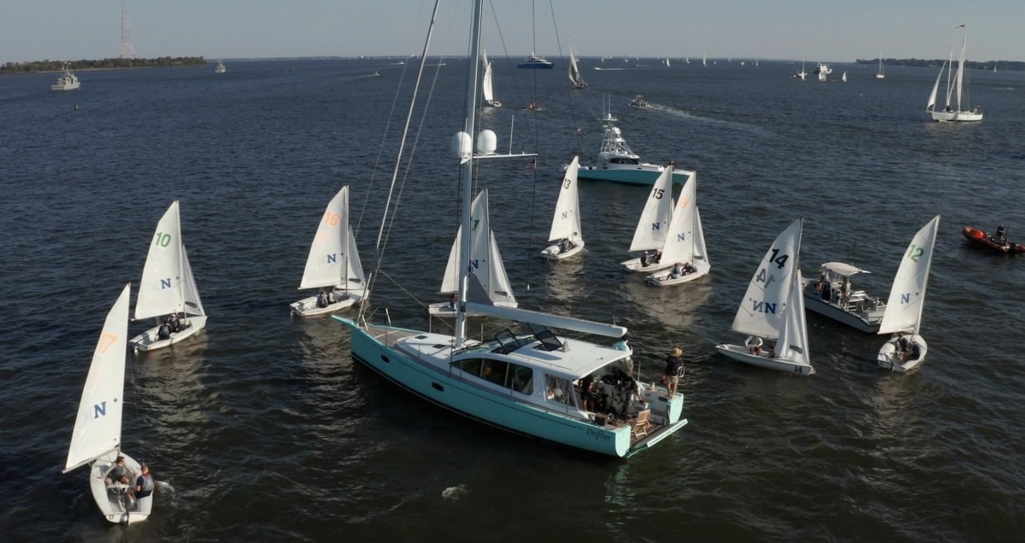 Sailboats gathered around a larger boat on open water